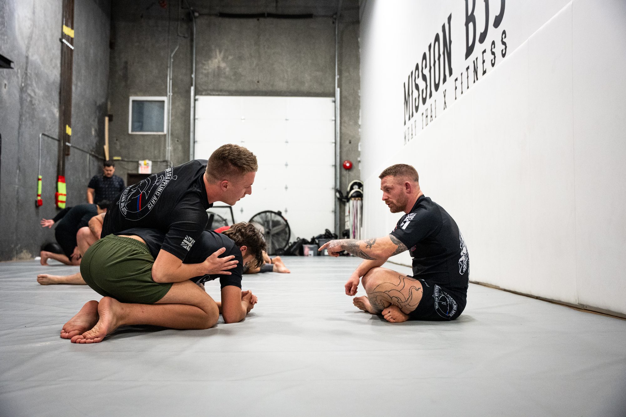 Athletes drilling No Gi grappling as a coach instructs on the mats at Mission BJJ in Mission, BC